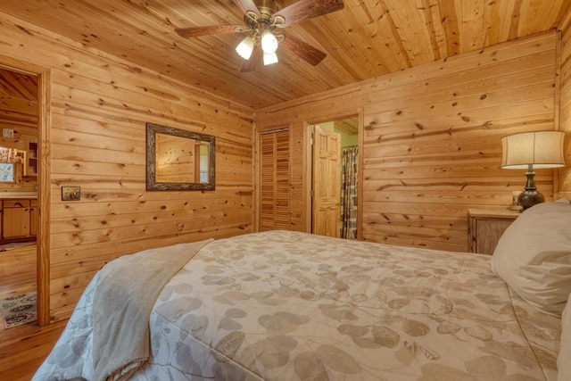 bedroom featuring wood walls, wood ceiling, ceiling fan, connected bathroom, and hardwood / wood-style flooring