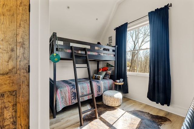 bedroom featuring lofted ceiling, wood finished floors, and baseboards