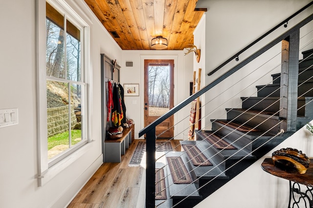 entrance foyer with wood ceiling, a healthy amount of sunlight, light wood-style flooring, and stairs