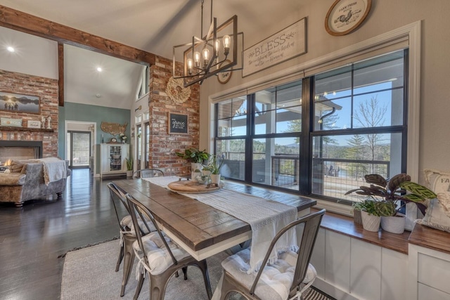 dining area featuring a warm lit fireplace, a wealth of natural light, dark wood finished floors, and beam ceiling