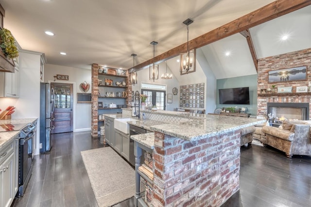 kitchen with pendant lighting, a large island, stainless steel appliances, open floor plan, and light stone countertops