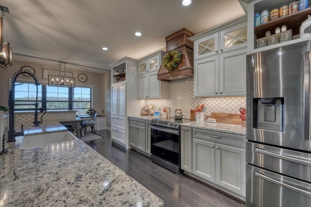 kitchen with stainless steel appliances, light stone counters, a sink, and decorative light fixtures