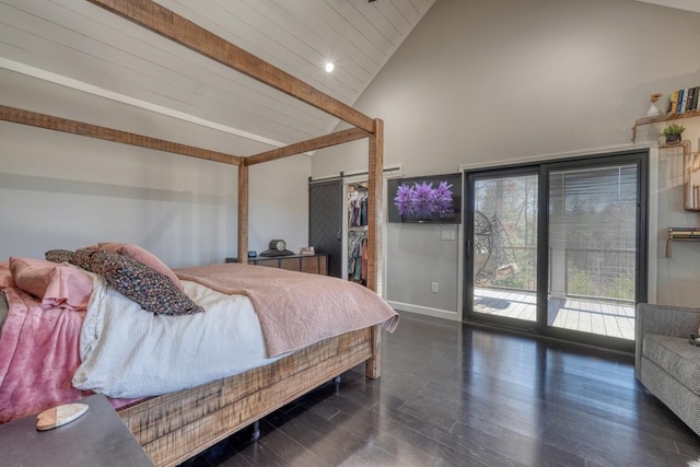 bedroom with a walk in closet, dark wood finished floors, a barn door, access to outside, and beamed ceiling