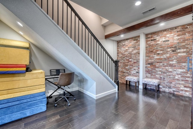 office area featuring visible vents, dark wood finished floors, baseboards, brick wall, and beam ceiling