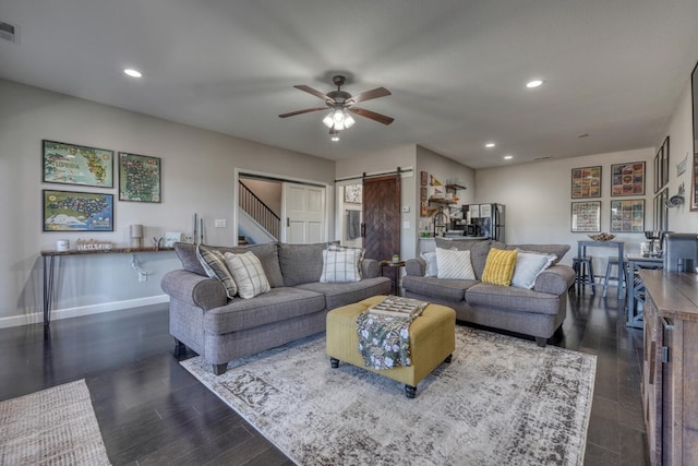 living area with a barn door, visible vents, baseboards, dark wood-style flooring, and recessed lighting