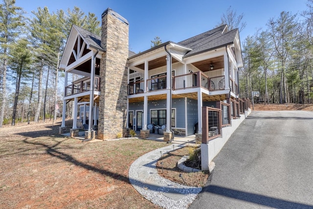 exterior space with ceiling fan, a chimney, and a balcony