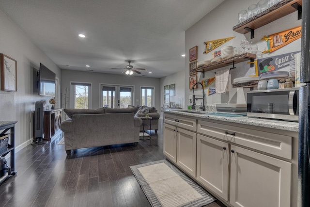 kitchen featuring white cabinets, light stone countertops, dark wood-style floors, open shelves, and stainless steel microwave