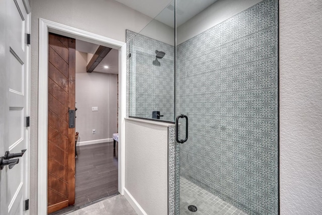 bathroom with a stall shower, wood finished floors, and baseboards