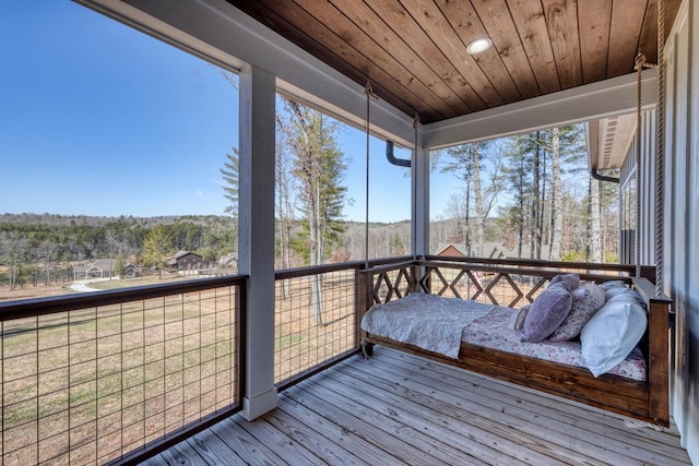 sunroom / solarium featuring a wealth of natural light, wooden ceiling, and a wooded view