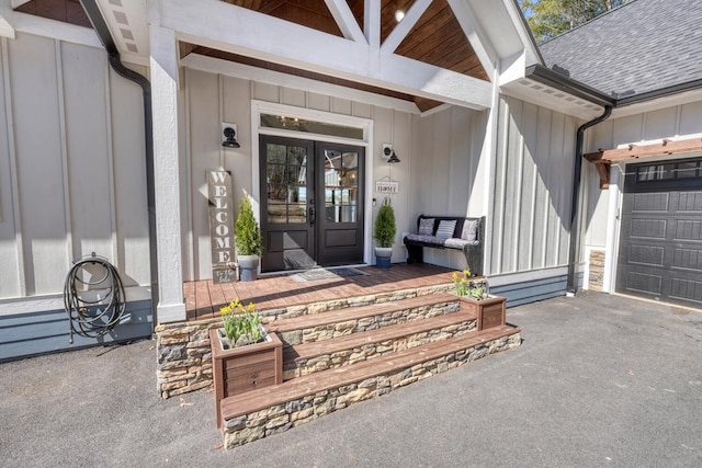 doorway to property featuring a porch, a shingled roof, driveway, french doors, and board and batten siding