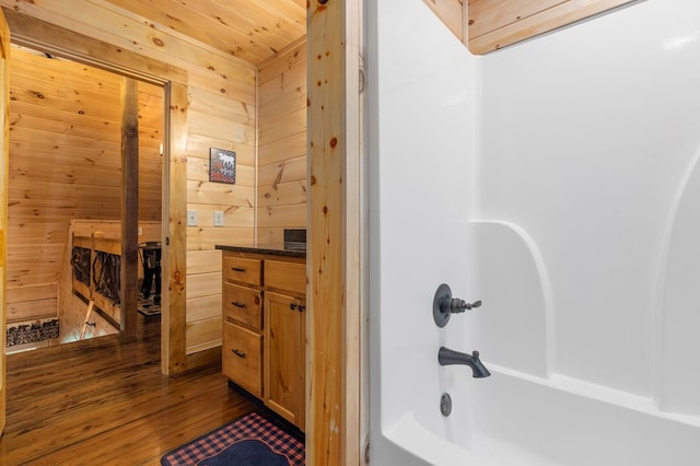 bathroom featuring vanity,  shower combination, wooden walls, wood ceiling, and hardwood / wood-style flooring