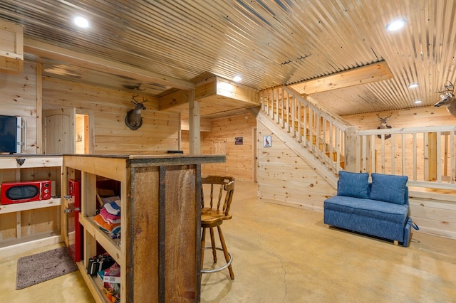 interior space featuring wood walls, concrete floors, and wooden ceiling