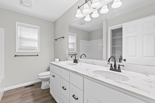 bathroom featuring vanity, toilet, wood-type flooring, and walk in shower