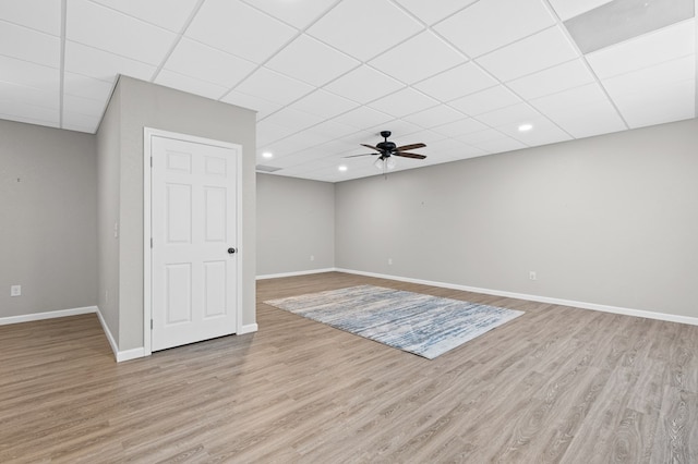 basement with a paneled ceiling, ceiling fan, and light hardwood / wood-style floors