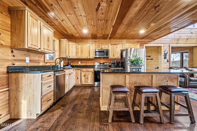 kitchen with wooden walls, light brown cabinets, stainless steel appliances, and dark hardwood / wood-style floors