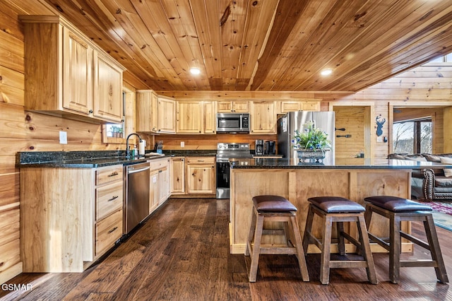 kitchen with wooden walls, light brown cabinets, stainless steel appliances, and dark hardwood / wood-style floors