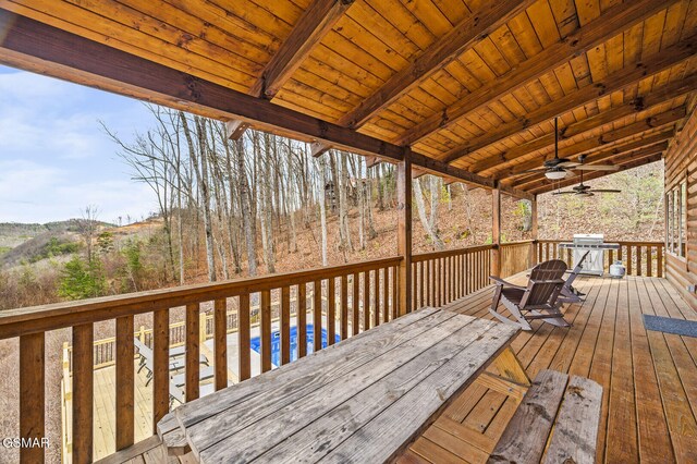 wooden terrace featuring area for grilling, ceiling fan, and a pool