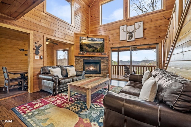 living room with wooden walls, a fireplace, high vaulted ceiling, and dark wood-type flooring