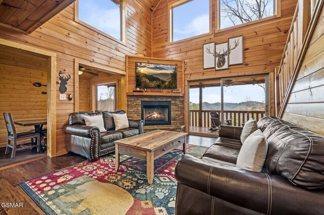 living room with wooden walls, a fireplace, high vaulted ceiling, and dark wood-type flooring