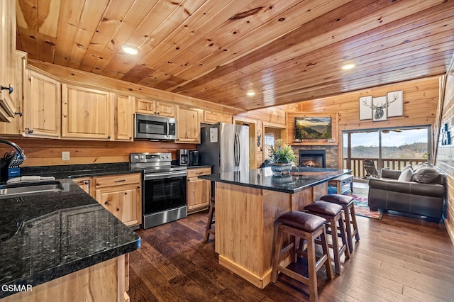 kitchen featuring a center island, wood walls, sink, dark hardwood / wood-style floors, and appliances with stainless steel finishes