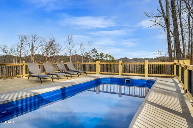 view of swimming pool with a deck with mountain view