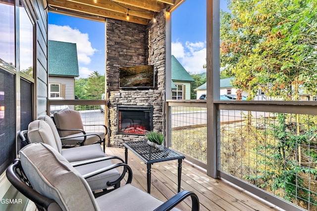 wooden deck featuring an outdoor stone fireplace