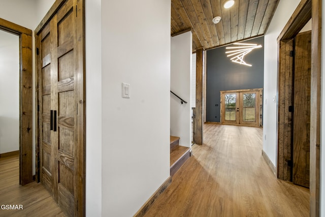 hallway featuring wood finished floors, wooden ceiling, baseboards, stairs, and vaulted ceiling