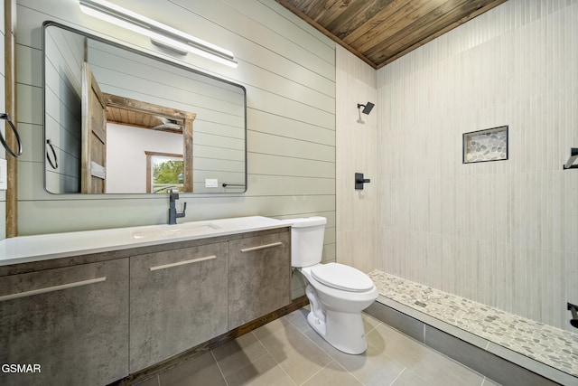 bathroom with tile patterned flooring, toilet, wood ceiling, tiled shower, and vanity