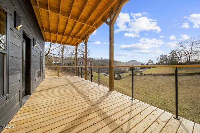 deck with a rural view, a mountain view, and a yard