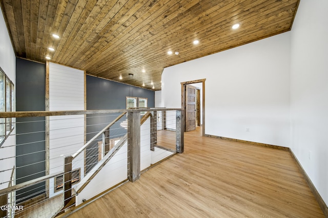 hall with an upstairs landing, wood ceiling, baseboards, and wood finished floors