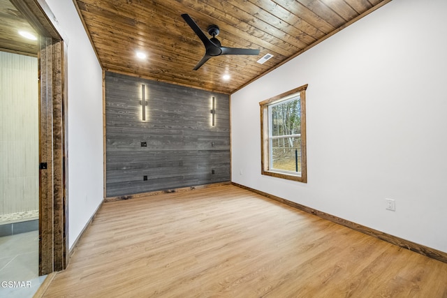 empty room featuring wooden walls, wooden ceiling, visible vents, and wood finished floors