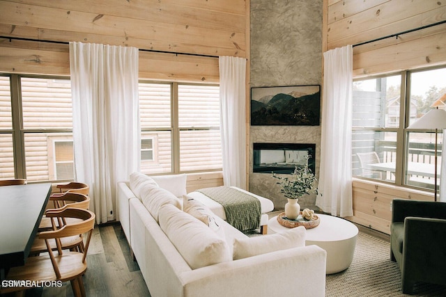 living room featuring a multi sided fireplace, wood-type flooring, and wooden walls