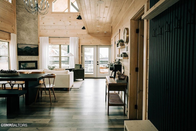 dining space featuring wood ceiling, hardwood / wood-style flooring, a large fireplace, french doors, and wood walls