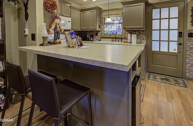 2846 Mountain View Cir, Sevierville, TN 37862 - kitchen featuring white microwave, a breakfast bar, light wood finished floors, decorative backsplash, and light countertops