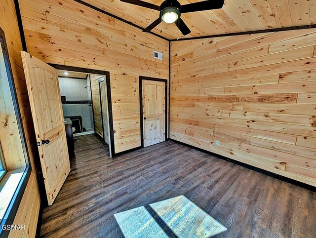 unfurnished bedroom with wood ceiling, ceiling fan, dark hardwood / wood-style floors, lofted ceiling, and wood walls