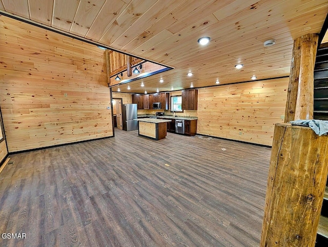 kitchen featuring stainless steel appliances, dark hardwood / wood-style floors, wooden ceiling, and wood walls