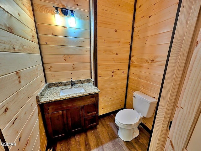 bathroom featuring vanity, wood walls, toilet, and wood-type flooring