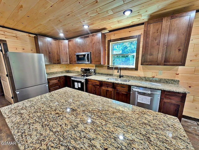 kitchen with light stone countertops, appliances with stainless steel finishes, wood ceiling, sink, and wood walls