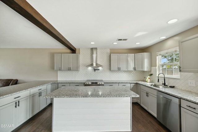 kitchen with sink, a kitchen island, wall chimney range hood, and appliances with stainless steel finishes