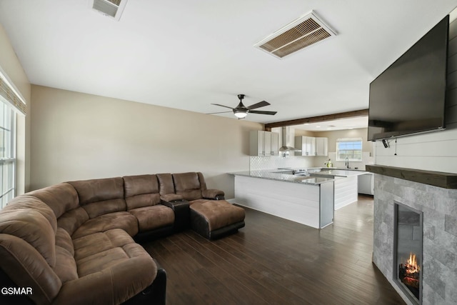 living room with beamed ceiling, dark hardwood / wood-style floors, ceiling fan, and sink