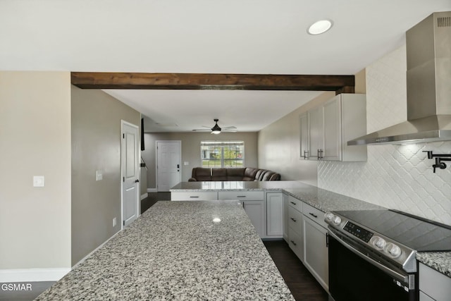 kitchen featuring light stone counters, stainless steel range with electric stovetop, and wall chimney range hood