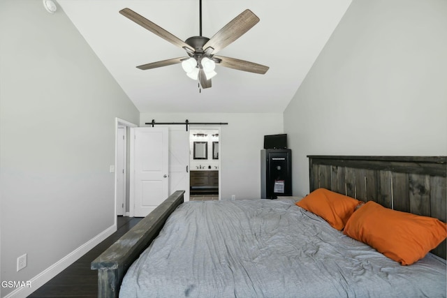 bedroom featuring ensuite bathroom, vaulted ceiling, ceiling fan, a barn door, and dark hardwood / wood-style floors