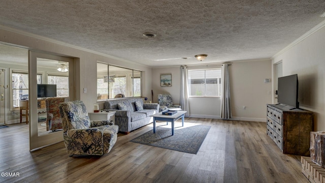 living area with a textured ceiling, visible vents, crown molding, wood finished floors, and a ceiling fan