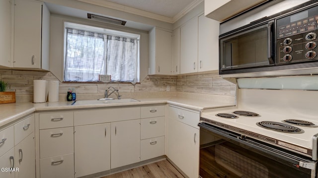 kitchen featuring black microwave, range with electric stovetop, light countertops, and a sink
