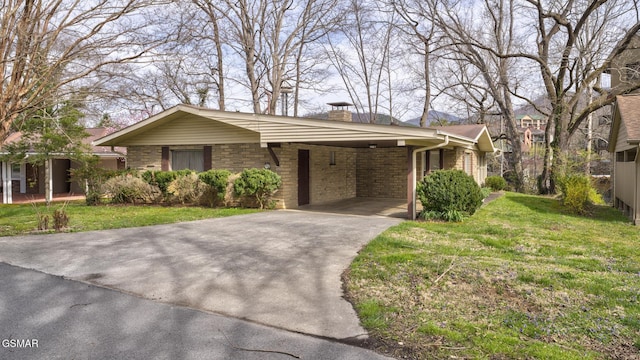 view of front facade featuring an attached carport, driveway, a chimney, and a front lawn