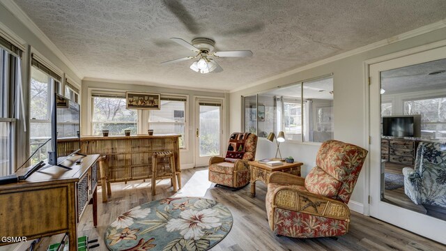sunroom / solarium with wood finished floors, ornamental molding, and a textured ceiling