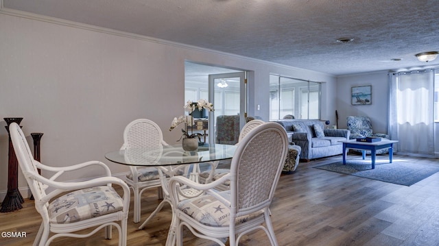 dining area featuring crown molding, a textured ceiling, and wood finished floors