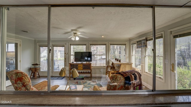 sunroom / solarium with a wealth of natural light, ornamental molding, baseboards, and a textured ceiling