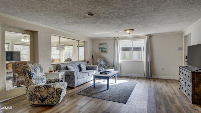 living area with baseboards, visible vents, wood finished floors, and ornamental molding