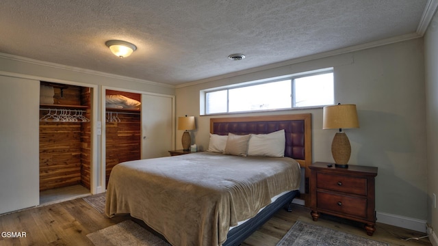 bedroom featuring wood finished floors, a textured ceiling, multiple closets, and visible vents
